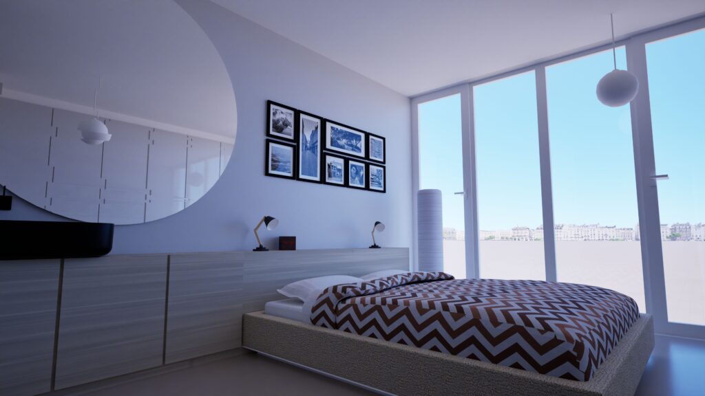 Modern bedroom interior with a large window overlooking a waterfront cityscape, featuring a low platform bed with a chevron patterned duvet, minimalist bedside lamps, and a gallery wall of black and white framed photographs, all within a clean, contemporary design. By Modify Architects
