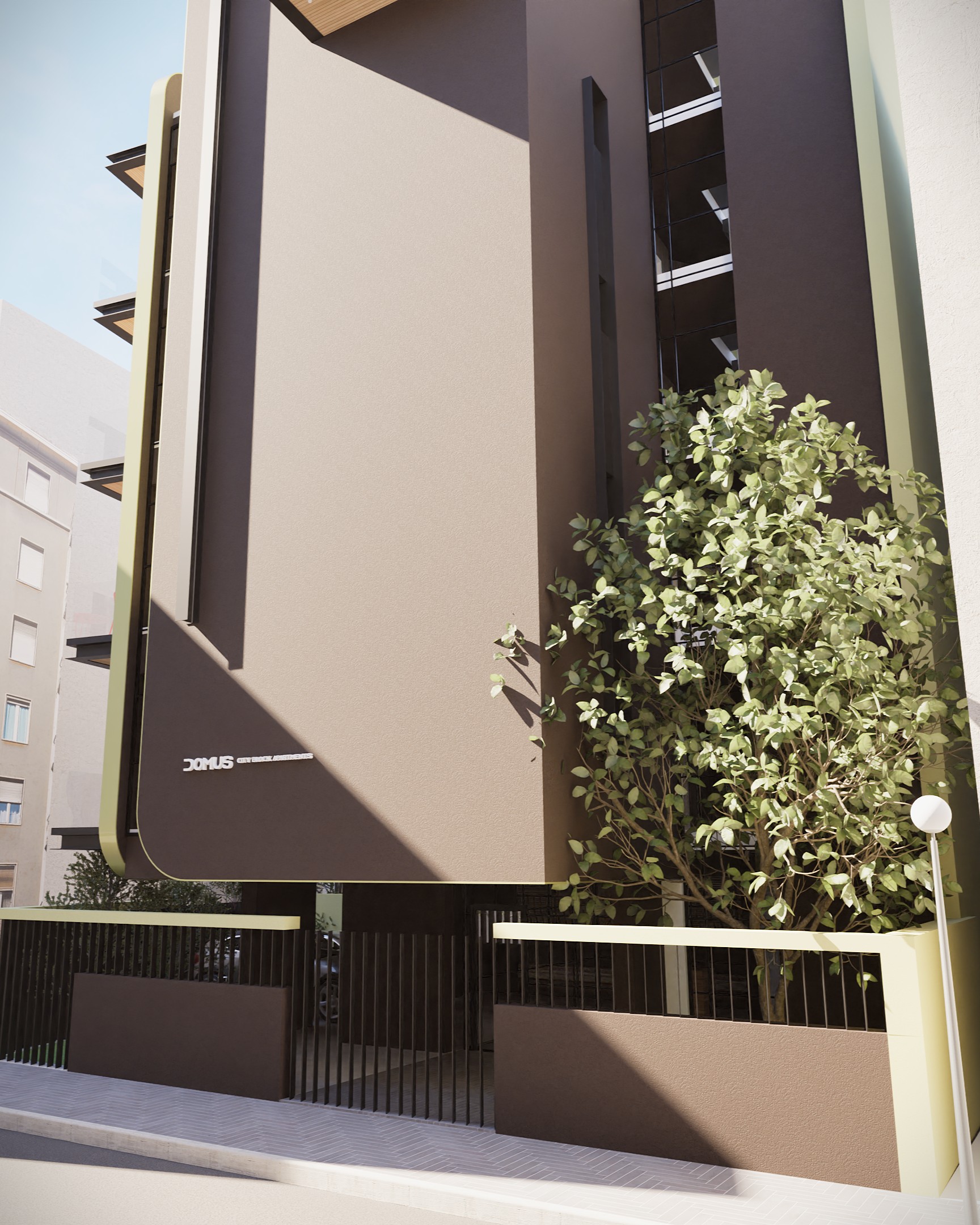 A low-angle view of a modern residential building exterior with a textured brown facade, dark metal accents, and a small tree in front of a gated entrance. The building features balconies and a minimalist design, set against a clear blue sky with neighboring buildings visible in the background. By Modify Architects